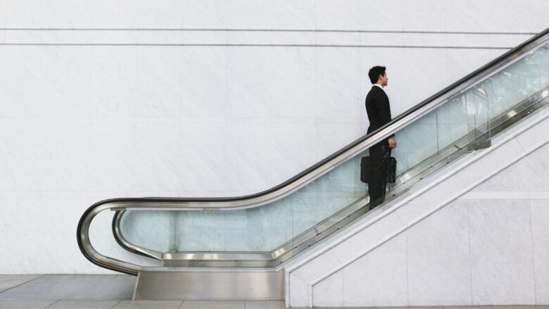 1人でエスカレーターに乗る男性のイメージ